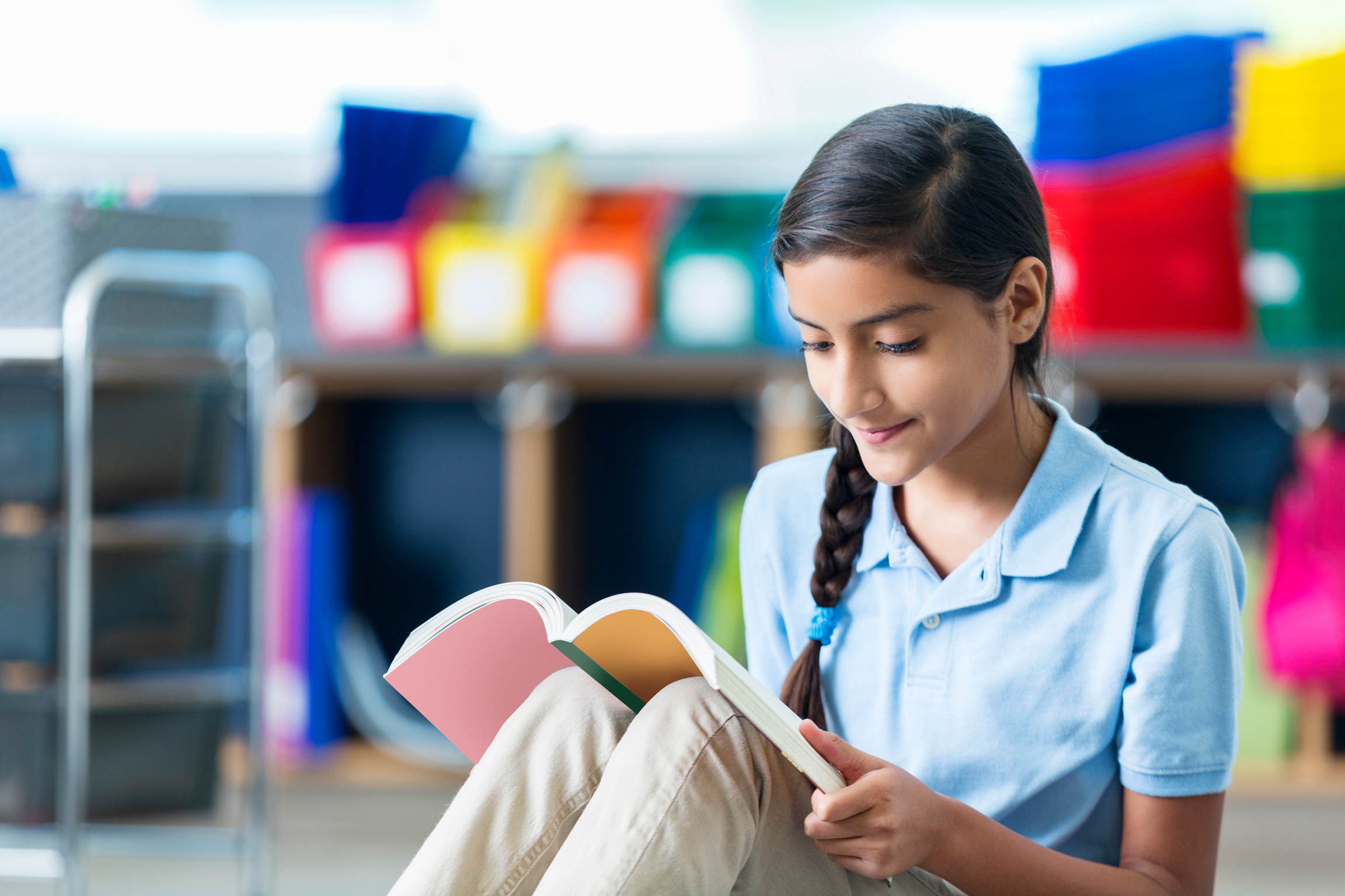 Focused middle school student reads book in library